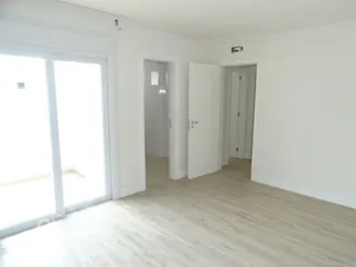 Ambiente interno com piso de madeira clara e portas de acesso.