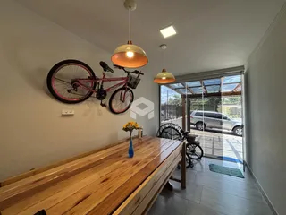 Uma sala de jantar com mesa de madeira e uma bicicleta na parede.