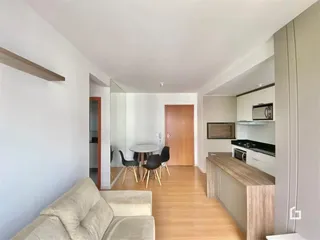 Sala de estar com cozinha e área de jantar integrada em um apartamento.
