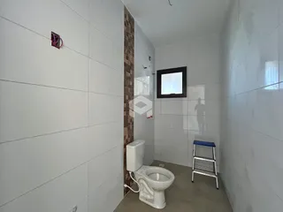 Foto interna de um banheiro com paredes brancas e piso claro.