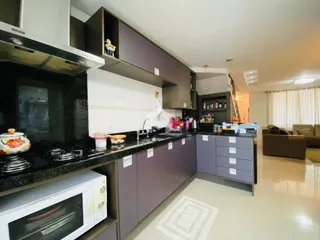 Uma cozinha moderna com armários e bancadas escuras é visível na imagem.