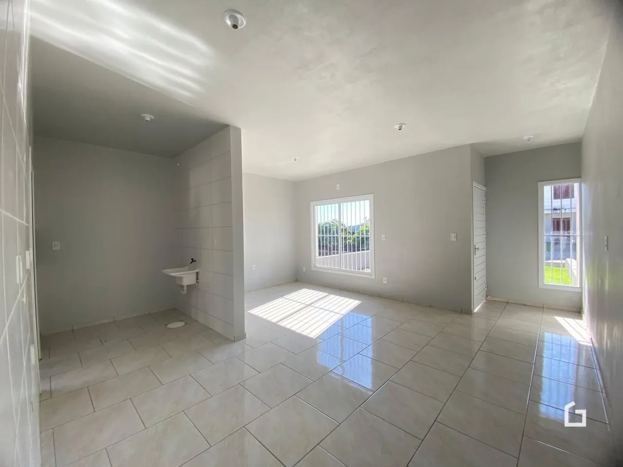 Um corredor interno com piso de cerâmica e uma janela.