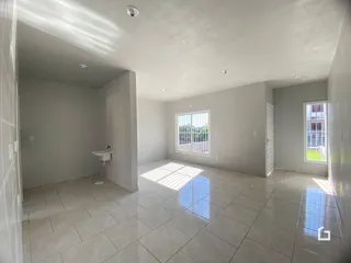 Um corredor interno com piso de cerâmica e uma janela.