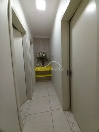 Foto de um corredor interno com paredes brancas e piso de azulejo claro.