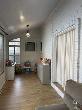 Sala de estar com paredes de tijolo branco e piso de madeira clara.
