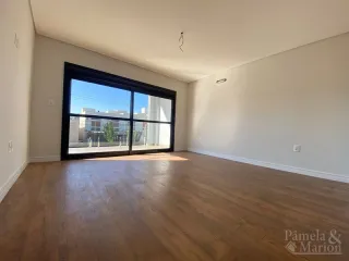Uma sala ampla com piso de madeira e grande janela.