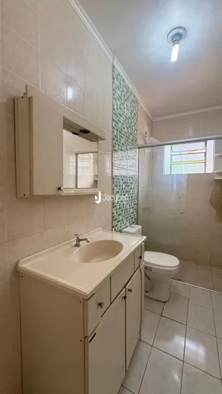 Um banheiro com revestimento cerâmico e louças brancas.