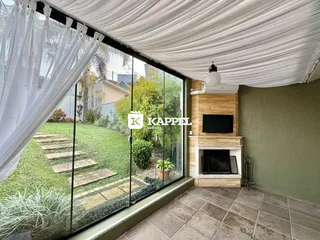 Sala de estar com vista para um jardim verde através de grandes janelas.