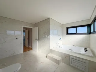 Imagem de um banheiro com revestimento em mármore claro e banheira branca.