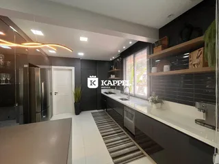 Cozinha moderna com armários escuros e bancadas brancas em um ambiente bem iluminado.