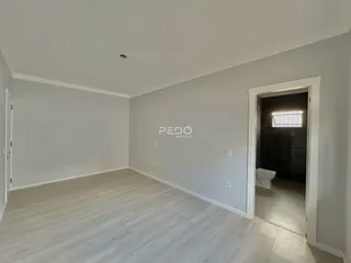 Ambiente interno de uma sala com piso de madeira clara e paredes brancas.