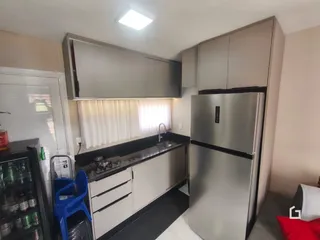 Cozinha moderna com armários brancos e eletrodomésticos em aço inoxidável.