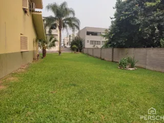 Gramado verde com árvores ao fundo mostrando uma área externa.