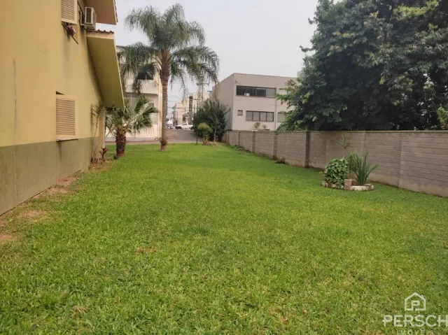 Gramado verde com árvores ao fundo mostrando uma área externa.