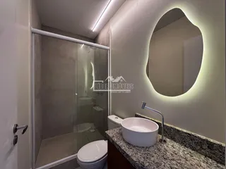 Interior de um banheiro com box de vidro e bancada de granito.