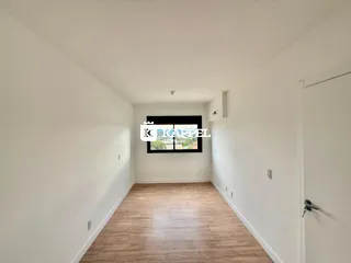 Hall de entrada com piso de madeira clara e paredes brancas.