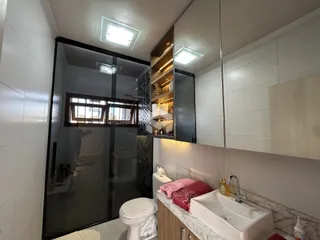 Banheiro moderno com box de vidro e bancada de mármore.