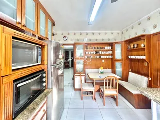 Sala de jantar com armários de madeira e cozinha integrada em Lajeado.