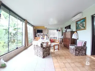 Sala de estar com grandes janelas que dão vista para a natureza.