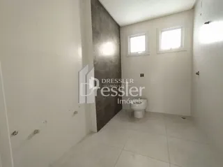Interior de um ambiente com paredes brancas e uma parede de destaque de concreto.