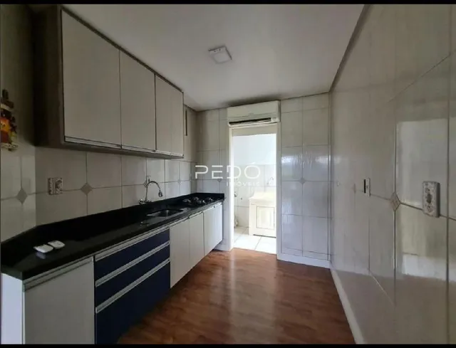 Interior da cozinha com armários brancos e piso de madeira.