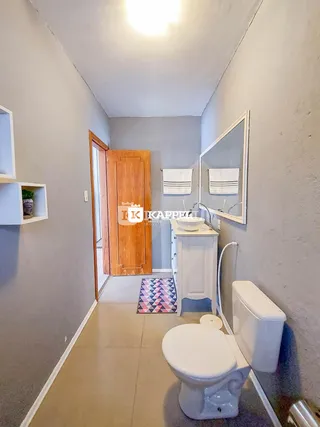 Foto de um banheiro com vaso sanitário e pia branca.