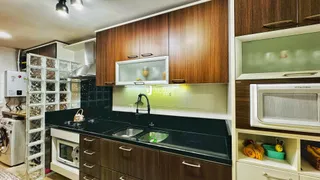 Cozinha moderna com armários de madeira e bancadas escuras.