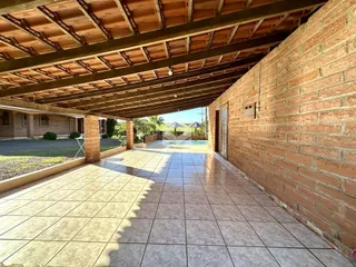 Vista de um pátio externo com piso de cerâmica e parede de tijolos.