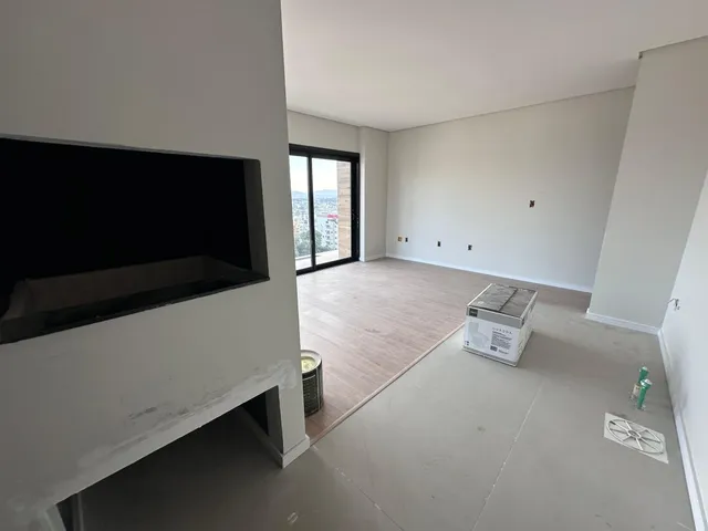 Foto interna de uma sala com parede branca e televisão.