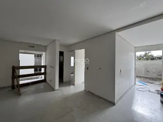 Vista de um corredor interno com paredes brancas e piso de concreto.