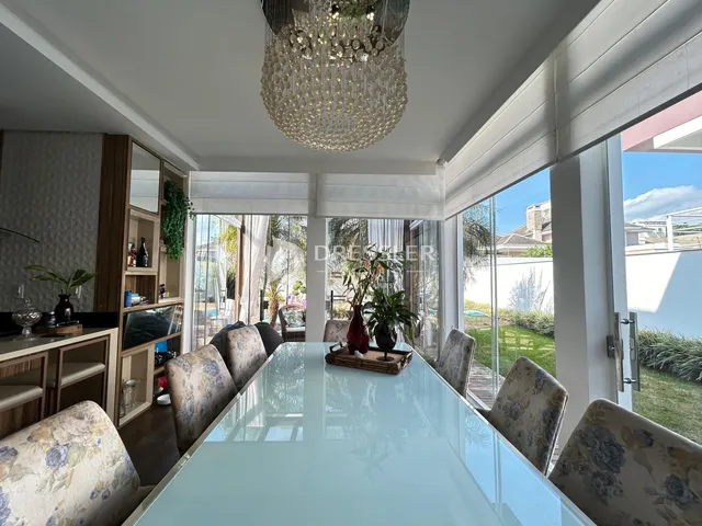 Vista de uma sala de jantar com grandes portas de vidro que dão acesso ao jardim.