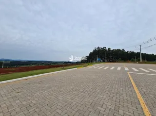 Vista externa de uma área pavimentada com paisagem ao fundo.
