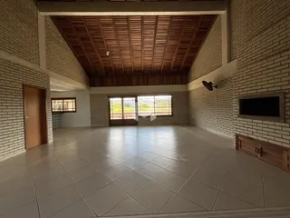 Sala ampla com piso de cerâmica e teto de madeira em um imóvel.