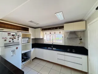 Foto da cozinha com armários brancos e bancada escura.