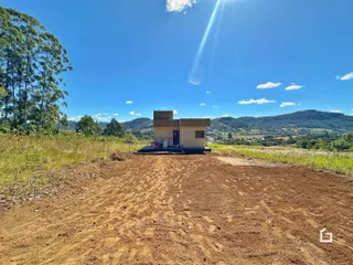 Foto da fachada de uma casa em uma área com paisagem de colinas ao fundo.