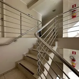 Foto de uma escadaria com corrimão metálico em um interior de imóvel.