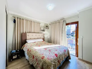 Quarto com cama e cortinas em ambiente claro.