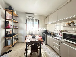 Cozinha com armários brancos e mesa de jantar de madeira.