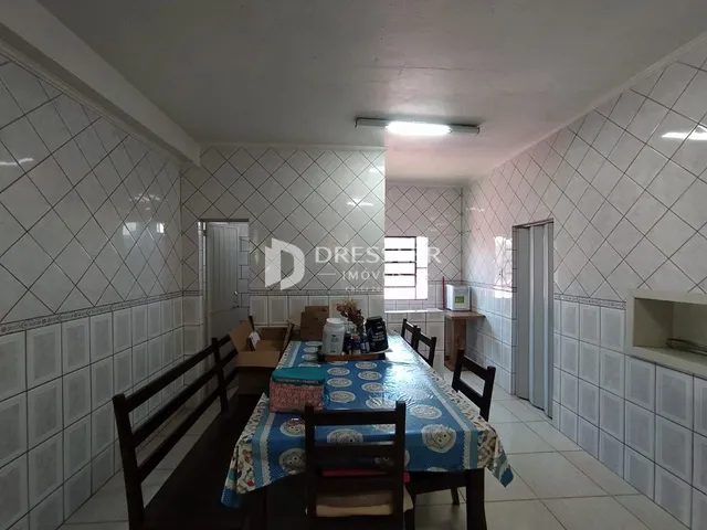 Uma sala de jantar com mesa e cadeiras em um ambiente de azulejos brancos.