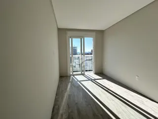 Interior de um ambiente com piso de madeira e vista para a cidade.