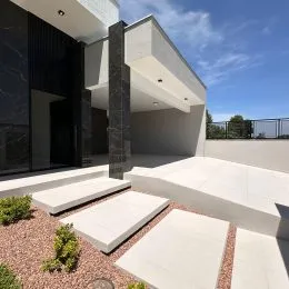 Fachada moderna de uma residência com revestimento claro e degraus de concreto em Lajeado.