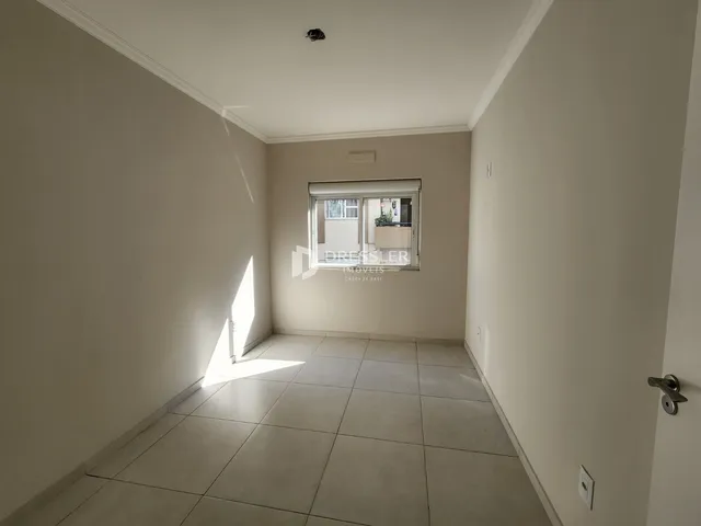 Corredor interno com piso de cerâmica e janela.