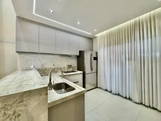 Cozinha moderna com bancadas de mármore e armários brancos.