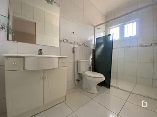 Banheiro com revestimento branco e piso cerâmico.