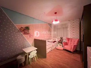 Quarto com cama e poltrona em ambiente com teto inclinado.