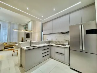 Cozinha moderna com armários brancos e bancadas de mármore clara.