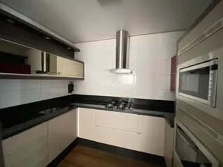 Vista da cozinha com armários brancos e bancadas escuras.
