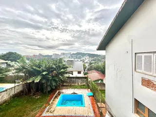 Vista externa de um quintal com piscina e vegetação.