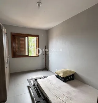 Quarto com janela de madeira e cama no interior da residência.