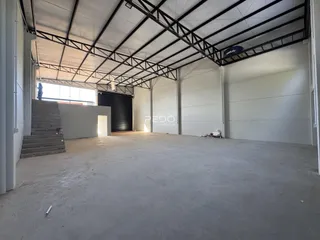 Vista interna de um espaço amplo e em construção com estrutura metálica exposta.
